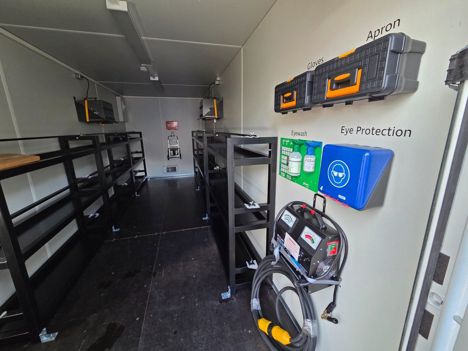 Interior of a mobile battery shop with steel racking, battery tester and safety stations
